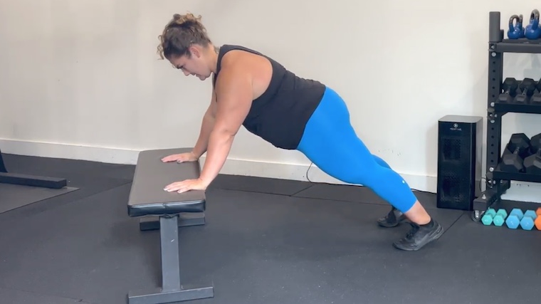 person doing push-ups with hands on bench