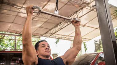 Muscular person in gym doing lat pulldown