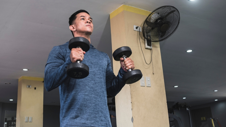 Man in gym performing curl with two dumbbells