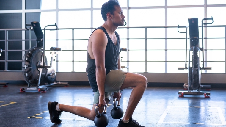 person in gym doing lunges with rounded shoulders