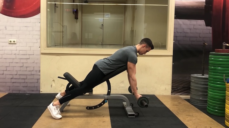 person in gym on bench curling barbell