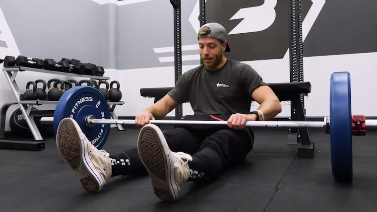 person in gym on floor with barbell